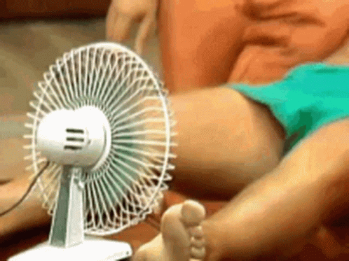 A Person Is Sitting In Front Of A Fan With Their Feet In Front Of It GIF