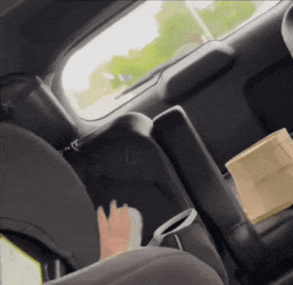 A Person Is Sitting In The Back Seat Of A Car With A Bag In The Trunk . GIF