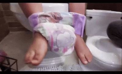 A Person Is Sitting On A Toilet With Their Feet In A Diaper . GIF