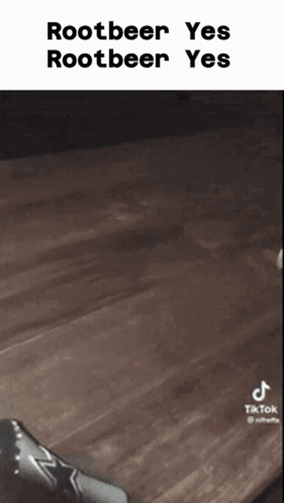 A Person Is Sitting On A Wooden Table With A Bottle Of Rootbeer In Front Of Them . GIF