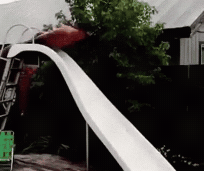 A Person Is Sliding Down A Slide In A Backyard GIF