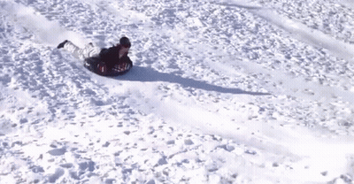 A Person Is Sliding Down A Snowy Hill On A Snow Tube GIF