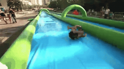 A Person Is Sliding Down An Inflatable Water Slide In A Park GIF