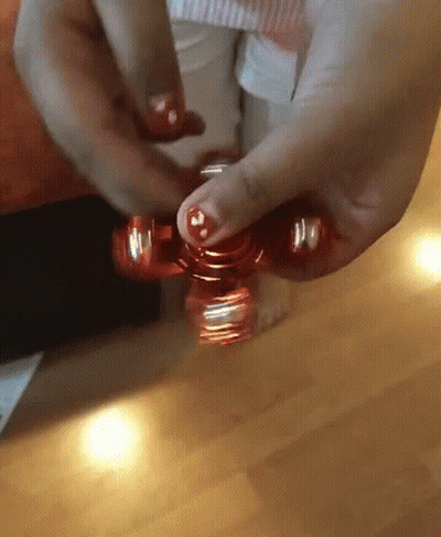 A Person Is Spinning A Red Fidget Spinner In Their Hand GIF