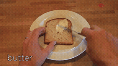 A Person Is Spreading Butter On A Piece Of Bread GIF
