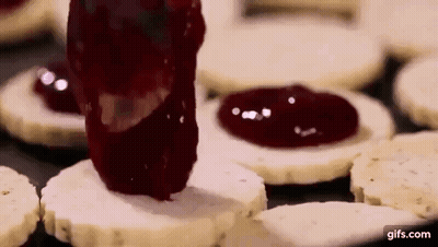 A Person Is Spreading Jam On A Cookie . GIF