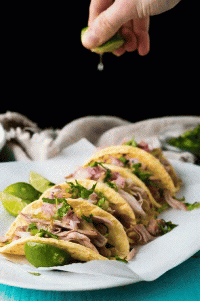 A Person Is Squeezing A Lime Over A Stack Of Tacos GIF