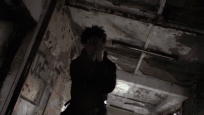 A Person Is Standing In A Dark Hallway With Their Hands On Their Face . GIF