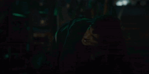 A Person Is Standing In A Dark Room With A Green Light Behind Them GIF