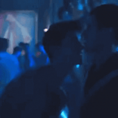 A Person Is Standing In A Dark Room With Blue Lights Behind Them GIF