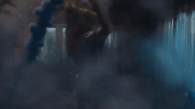 A Person Is Standing In A Dark Room With Smoke Coming Out Of The Window . GIF