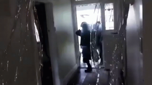 A Person Is Standing In A Hallway In Front Of A Glass Door . GIF