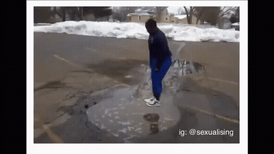 A Person Is Standing In A Puddle Of Water On The Side Of A Road . GIF