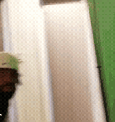 A Person Is Standing In A Room With A Green Wall . GIF