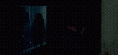 A Person Is Standing In A Room With Clothes Hanging On The Racks GIF