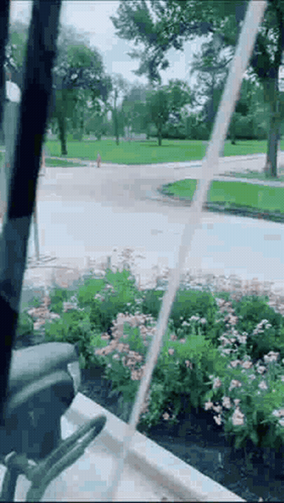 A Person Is Standing In Front Of A Fountain In A Park With Water Coming Out Of It . GIF