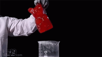 A Person Is Standing In Front Of A Glass Filled With Liquid And Smoke . GIF