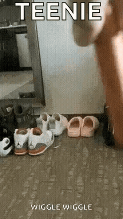 A Person Is Standing In Front Of A Mirror Next To A Row Of Shoes . GIF
