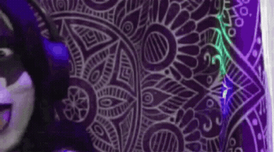 A Person Is Standing In Front Of A Purple Wall With A Purple Pattern On It . GIF