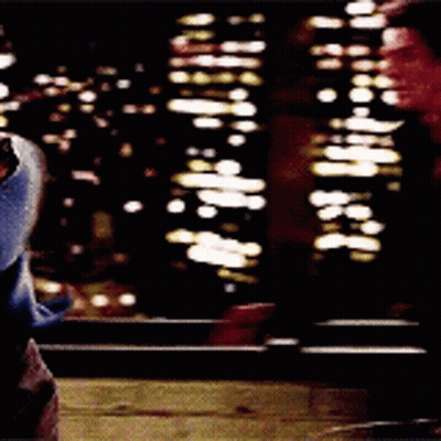 A Person Is Standing In Front Of A Window At Night Looking Out At The City Lights . GIF