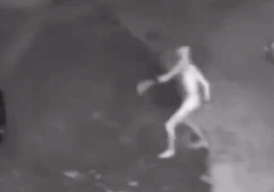 A Person Is Standing In The Dark With Their Arms Outstretched In A Black And White Photo . GIF