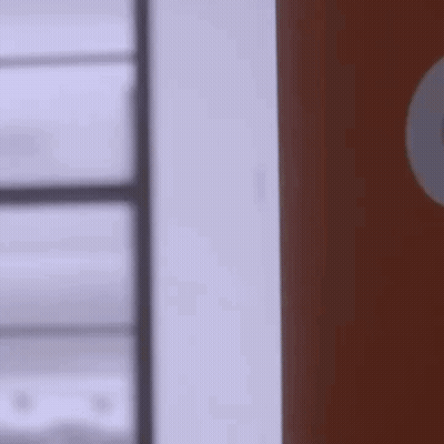 A Person Is Standing Next To A Door In A Room . GIF