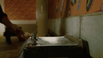 A Person Is Standing Next To A Water Fountain In A Room . GIF