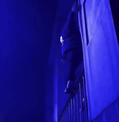 A Person Is Standing On A Balcony In A Dark Room With Blue Lights . GIF