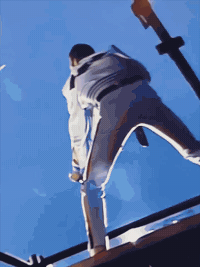 A Person Is Standing On A Railing With A Blue Sky Behind Them GIF