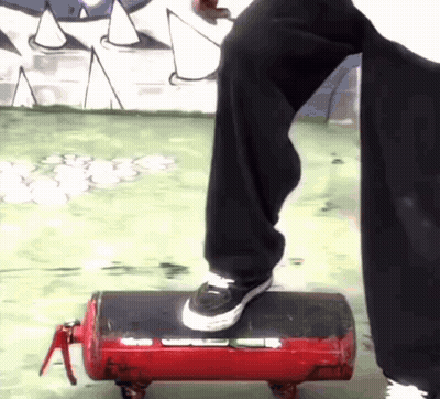 A Person Is Standing On A Red Fire Extinguisher With Wheels GIF