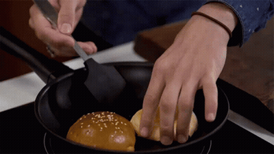 A Person Is Stirring A Hamburger Bun In A Frying Pan GIF
