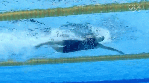 A Person Is Swimming In A Pool With The Olympic Rings Visible GIF