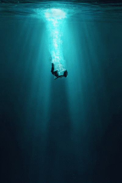 A Person Is Swimming In The Ocean With The Sun Shining Through GIF