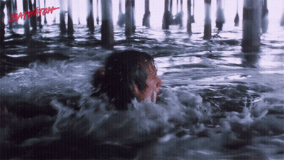 A Person Is Swimming Under A Pier And The Word Baywatch Is Visible GIF