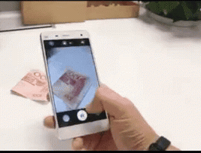 A Person Is Taking A Picture Of A Stack Of Money With A Cell Phone GIF