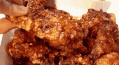 A Person Is Taking A Piece Of Fried Chicken From A Plate GIF