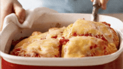 A Person Is Taking A Piece Of Pizza Out Of A Casserole Dish With A Fork GIF