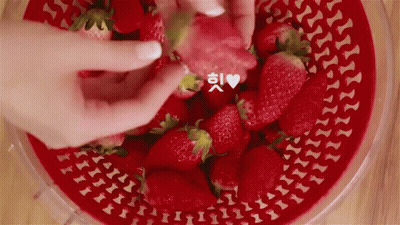 A Person Is Taking A Strawberry Out Of A Bowl Of Strawberries GIF