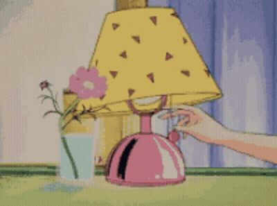 A Person Is Touching A Lamp Next To A Glass Of Milk .. GIF