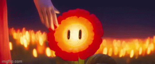 A Person Is Touching A Red Flower With A Face In Front Of A Bunch Of Candles . GIF
