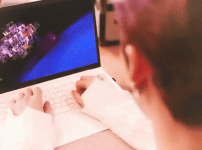 A Person Is Typing On A Laptop Computer While Sitting At A Desk . GIF