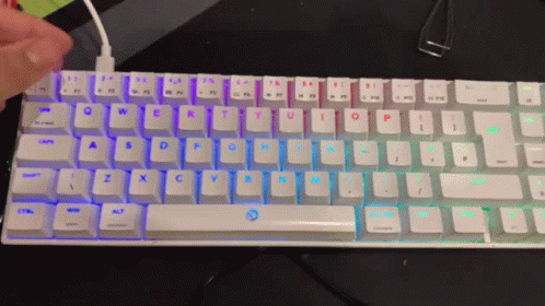 A Person Is Typing On A White Keyboard With A Rainbow Colored Backlight GIF