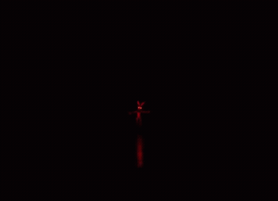 A Person Is Walking Down A Hallway With Red Lights On The Ceiling . GIF