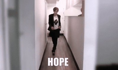 A Person Is Walking Down A Hallway With The Word Hope Written On The Floor . GIF