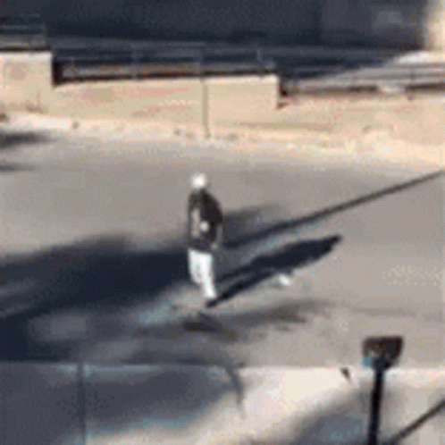 A Person Is Walking Down A Street With A Skateboard . GIF