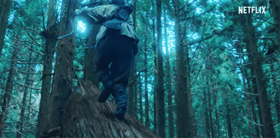 A Person Is Walking Through A Forest With A Backpack And A Light On Their Back . GIF