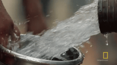 A Person Is Washing Their Hands In A Bucket Of Water From A Hose . GIF