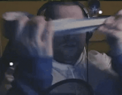A Person Is Wearing A Virtual Reality Headset And Headphones While Sitting In Front Of A Computer Screen . GIF