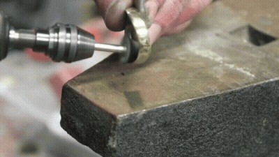 A Person Is Working On A Piece Of Metal With A Drill And Polisher . GIF