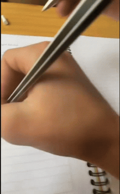 A Person Is Writing On A Notebook With A Pencil GIF